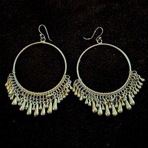 Silver metal big hoop earrings with beaded fringe bottoms. Hoops hang off ear pc